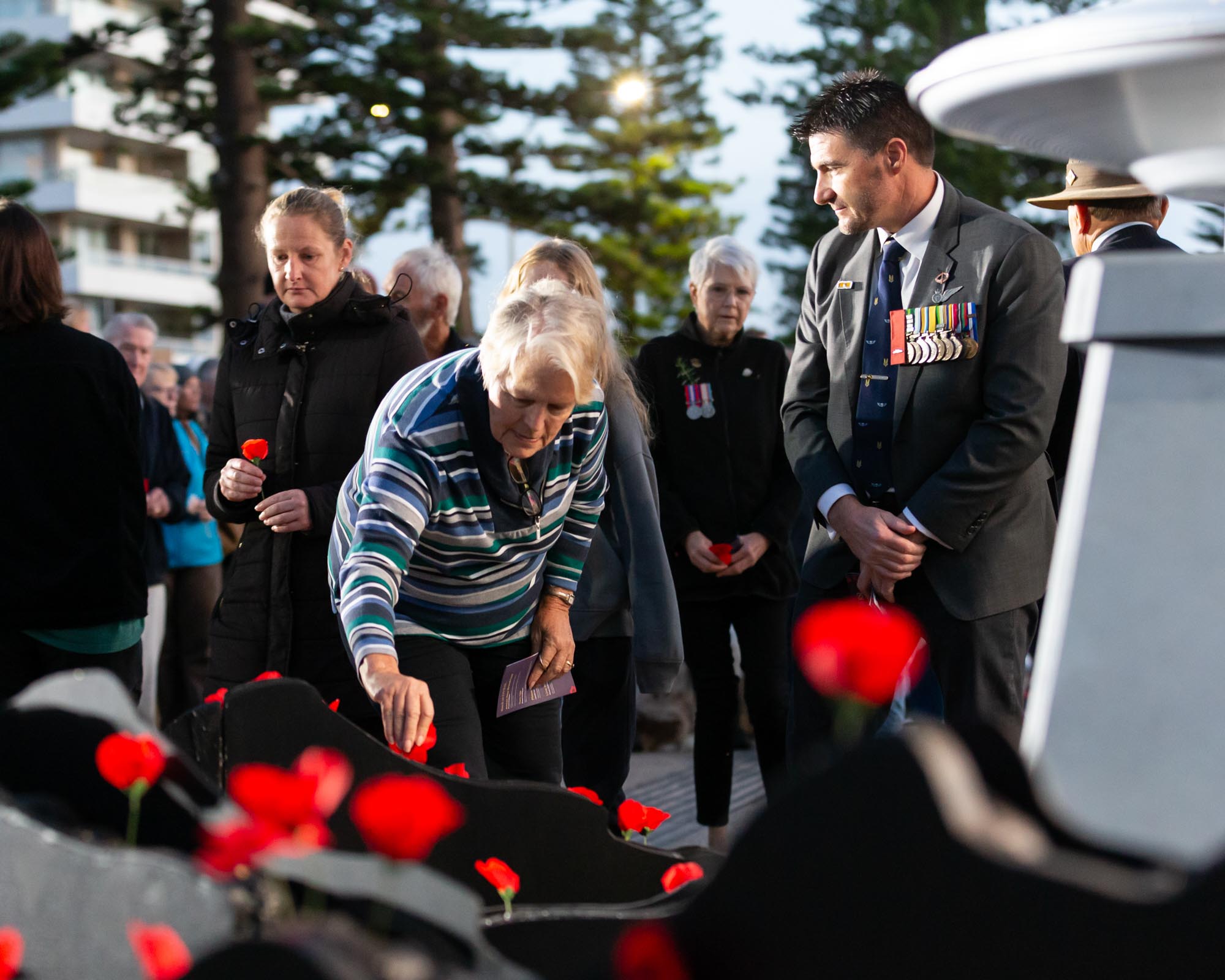 Lady laying a poppy Anzac Day Dawn Service Dee Why Beach
